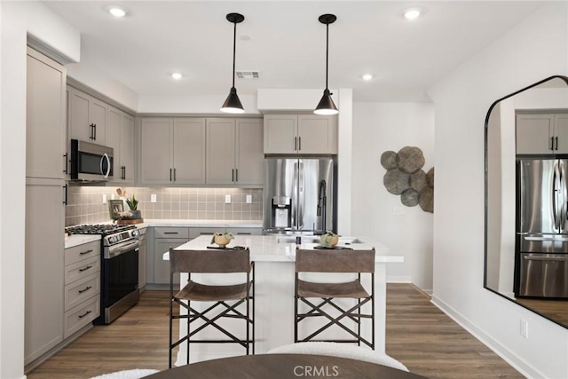 12247 Elliott Ave Unit F, El Monte, CA 91732 - kitchen with gray cabinets, appliances with stainless steel finishes, decorative backsplash, dark wood finished floors, and light countertops