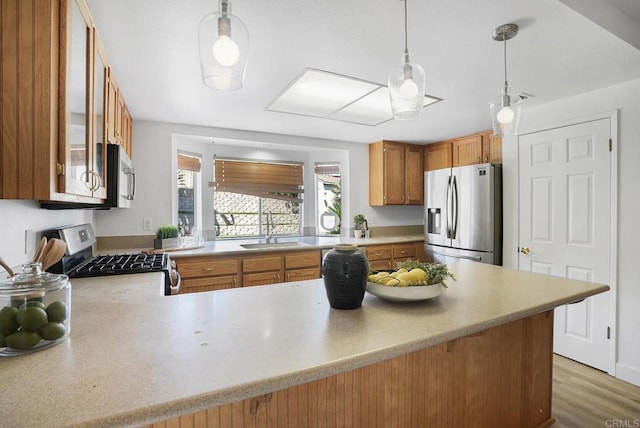 1930 Rosewood St, Vista, CA 92081 - kitchen with stainless steel appliances, light countertops, brown cabinetry, decorative light fixtures, and a peninsula