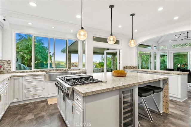 30282 Sonrisa, Laguna Niguel, CA 92677 - kitchen with beverage cooler, a kitchen island, white cabinetry, light stone countertops, and stainless steel gas cooktop