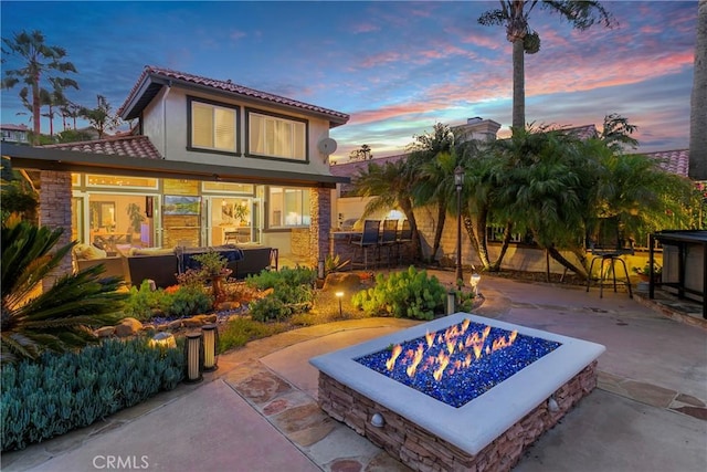 30282 Sonrisa, Laguna Niguel, CA 92677 - back of house at dusk with a fire pit, a patio area, a tiled roof, and stucco siding