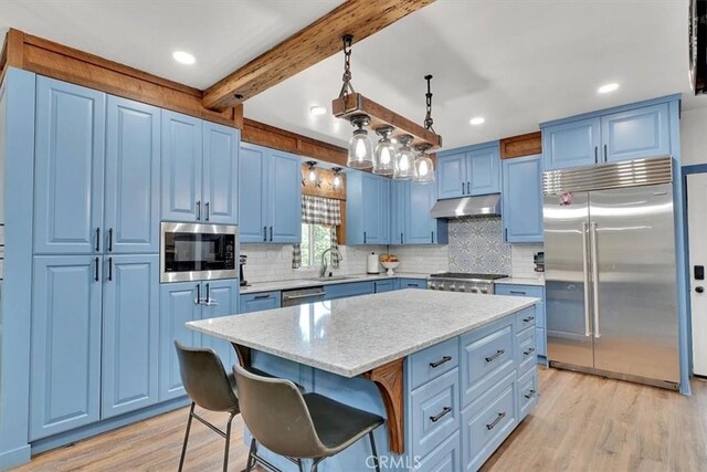 10784 Cole Way, Grass Valley, CA 95945 - kitchen with built in appliances, blue cabinetry, light wood-style floors, under cabinet range hood, and backsplash