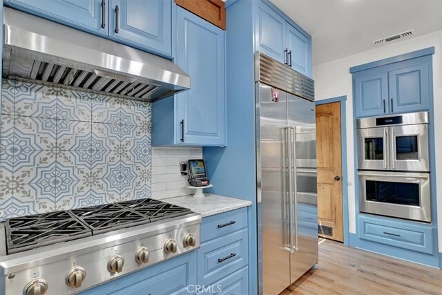 10784 Cole Way, Grass Valley, CA 95945 - kitchen featuring appliances with stainless steel finishes, under cabinet range hood, blue cabinetry, decorative backsplash, and light wood-type flooring