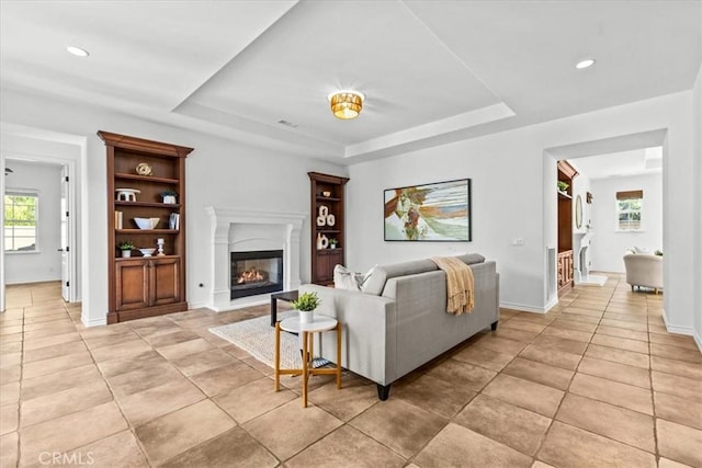 31521 Paseo Campeon, San Juan Capistrano, CA 92675 - living area with healthy amount of natural light, a tray ceiling, a glass covered fireplace, light tile patterned floors, and recessed lighting