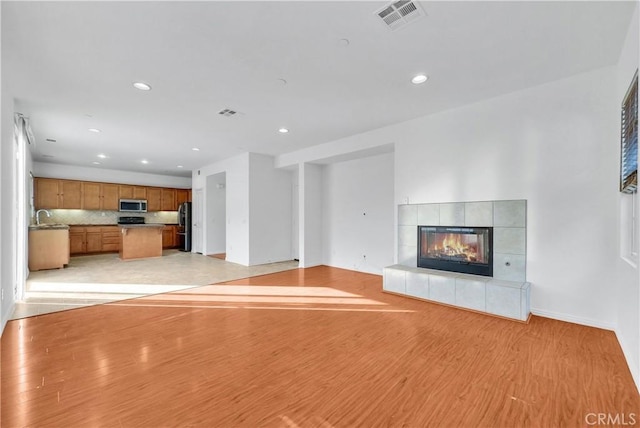 4564 Vincent Way, Riverside, CA 92501 - unfurnished living room featuring light wood finished floors, recessed lighting, and a tiled fireplace