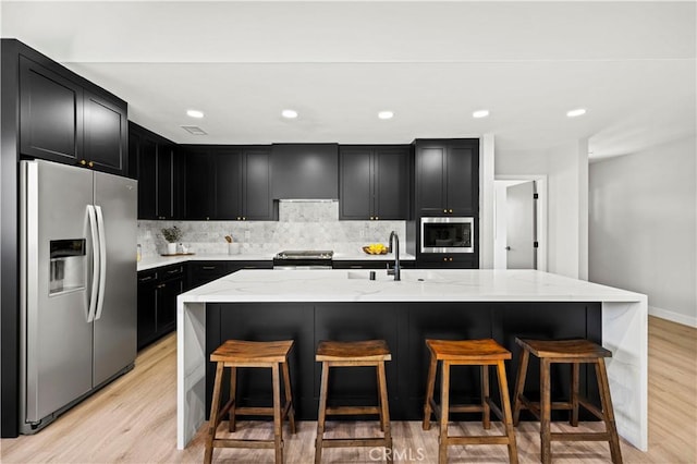 9712 Saloma Ave, North Hills, CA 91343 - kitchen featuring stainless steel appliances, dark cabinets, light stone countertops, light wood finished floors, and recessed lighting