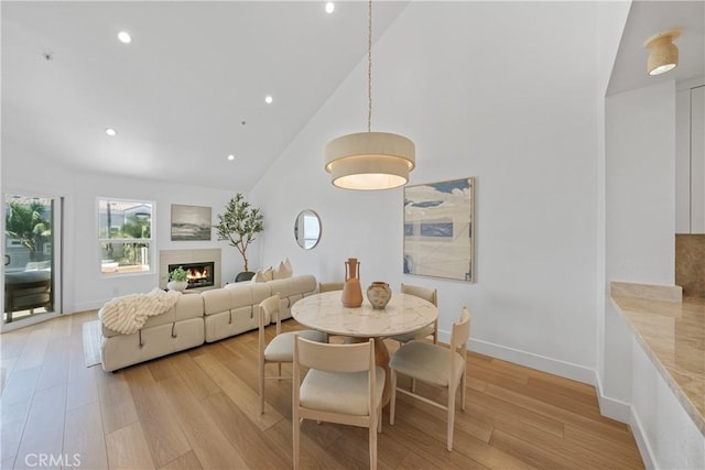 2000 Pacific Coast Hwy Unit 313, Huntington Beach, CA 92649 - dining space featuring high vaulted ceiling, light wood finished floors, a warm lit fireplace, and recessed lighting