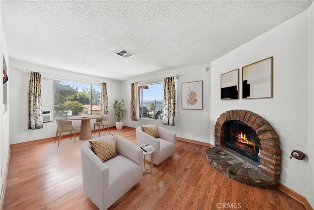 17162 Grand Ave, Lake Elsinore, CA 92530 - living area featuring wood finished floors, a brick fireplace, a textured ceiling, and cooling unit