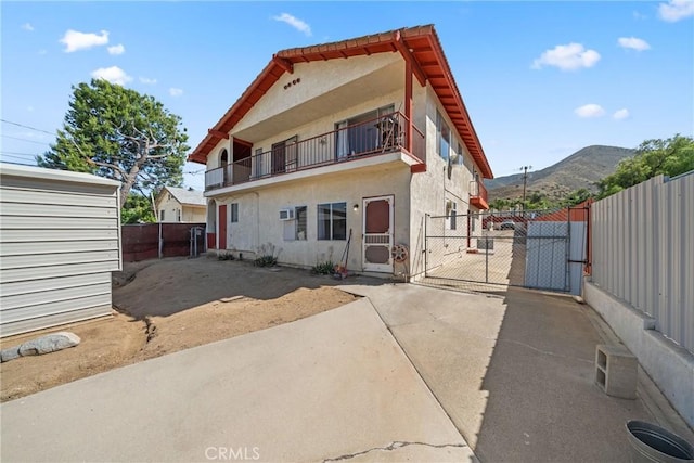 17162 Grand Ave, Lake Elsinore, CA 92530 - rear view of property featuring a gate, stucco siding, a balcony, and a mountain view