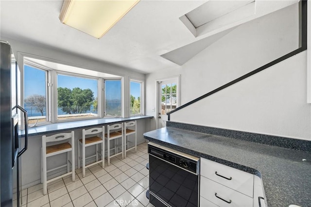 17162 Grand Ave, Lake Elsinore, CA 92530 - kitchen featuring black dishwasher, light tile patterned flooring, white cabinetry, and dark countertops