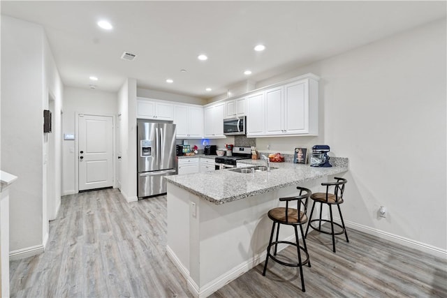 2848 E Berry Loop Privado Unit 52, Ontario, CA 91761 - kitchen with appliances with stainless steel finishes, a peninsula, light wood-type flooring, white cabinetry, and recessed lighting