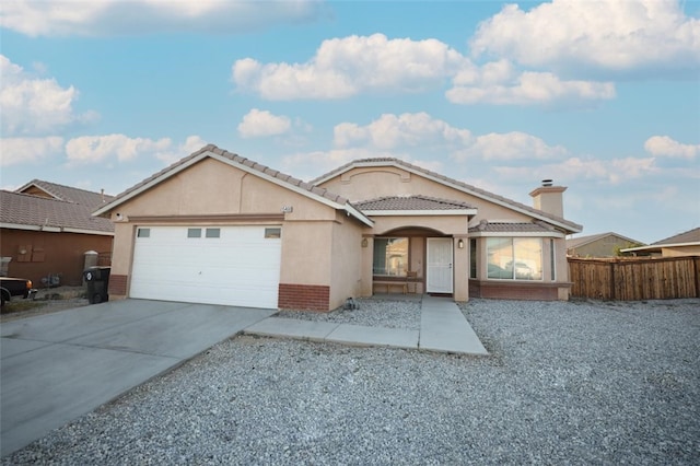 15460 Guava Way, Victorville, CA 92394 - view of front of home with a garage, stucco siding, driveway, brick siding, and a tiled roof