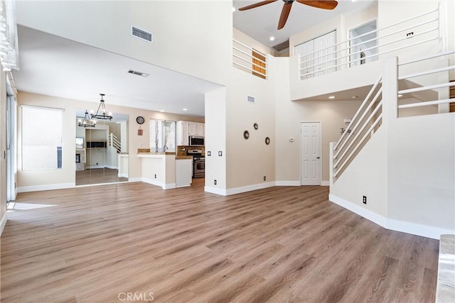 4441 Foxrun Dr, Chino Hills, CA 91709 - unfurnished living room with a ceiling fan, light wood-type flooring, stairs, a towering ceiling, and a chandelier
