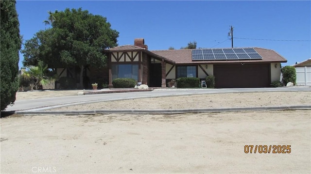 19824 Yucca Loma Rd, Apple Valley, CA 92307 - view of front facade featuring roof mounted solar panels, a chimney, a garage, a tiled roof, and stucco siding