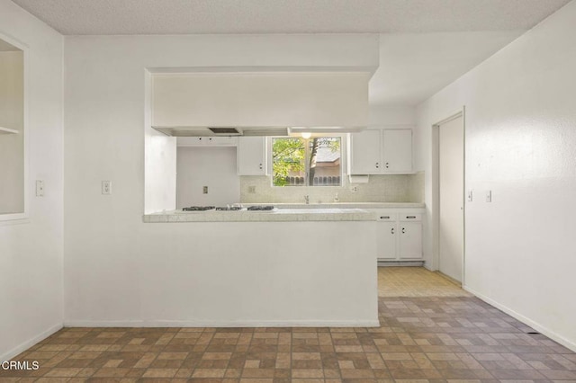 1543 Mobil Ave, Camarillo, CA 93010 - kitchen with white cabinetry, light countertops, white gas stovetop, backsplash, and a peninsula