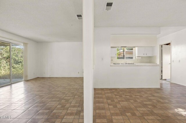 1543 Mobil Ave, Camarillo, CA 93010 - unfurnished living room with a textured ceiling and brick patterned floors