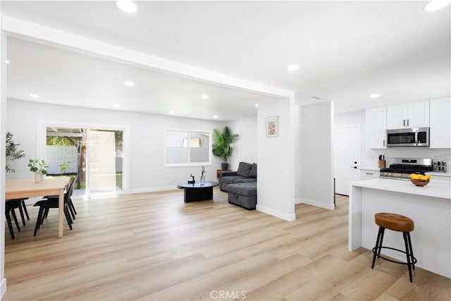 18746 Welby Way, Reseda, CA 91335 - kitchen with stainless steel appliances, white cabinetry, light countertops, a kitchen bar, and light wood-style flooring