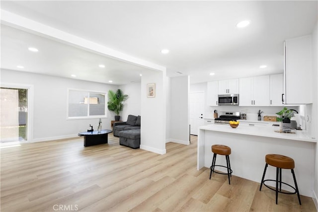 18746 Welby Way, Reseda, CA 91335 - kitchen featuring stainless steel appliances, a kitchen breakfast bar, light wood-type flooring, a peninsula, and white cabinets