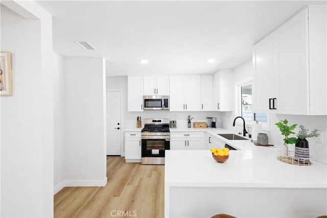 18746 Welby Way, Reseda, CA 91335 - kitchen with appliances with stainless steel finishes, light wood-style flooring, light countertops, recessed lighting, and white cabinetry