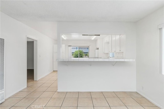 841 W 5th, San Pedro, CA 90731 - kitchen with tile counters, a breakfast bar area, a peninsula, white cabinetry, and light tile patterned floors
