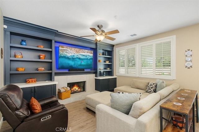 1647 Naranjo Ct, Redlands, CA 92374 - living area featuring built in shelves, ceiling fan, a tiled fireplace, and wood finished floors