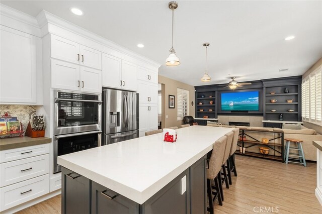 1647 Naranjo Ct, Redlands, CA 92374 - kitchen with stainless steel appliances, ceiling fan, light wood-style flooring, open floor plan, and white cabinetry