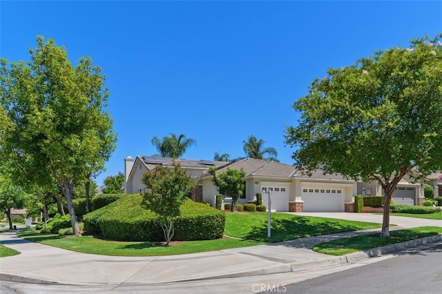 1647 Naranjo Ct, Redlands, CA 92374 - obstructed view of property with a garage, roof mounted solar panels, concrete driveway, a front yard, and stucco siding