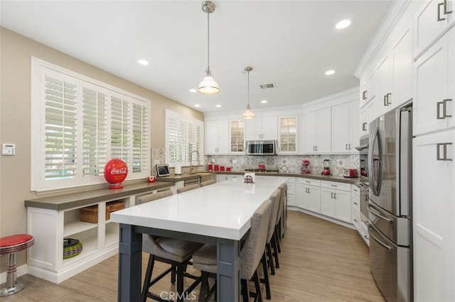 1647 Naranjo Ct, Redlands, CA 92374 - kitchen featuring appliances with stainless steel finishes, a kitchen bar, tasteful backsplash, white cabinets, and glass insert cabinets