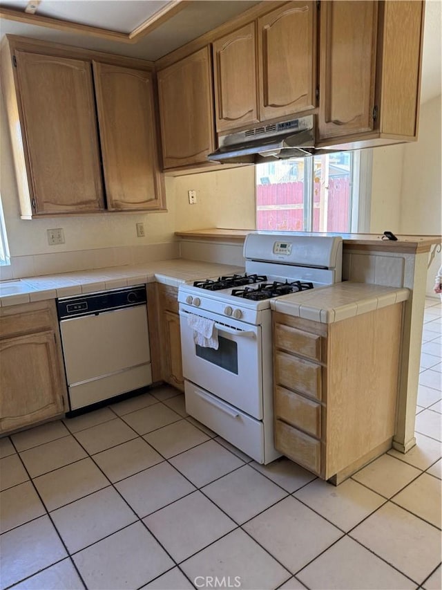 43644 Serenity Ct, Lancaster, CA 93535 - kitchen with white appliances, under cabinet range hood, tile countertops, light tile patterned flooring, and light brown cabinetry