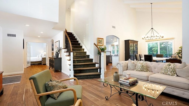 31962 Via Montura, San Juan Capistrano, CA 92675 - living room featuring arched walkways, stairway, a towering ceiling, a chandelier, and wood finished floors
