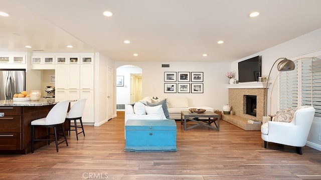 31962 Via Montura, San Juan Capistrano, CA 92675 - living room featuring arched walkways, recessed lighting, light wood finished floors, and a fireplace with raised hearth