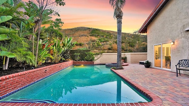 31962 Via Montura, San Juan Capistrano, CA 92675 - pool at dusk with a pool with connected hot tub, a patio area, and a mountain view