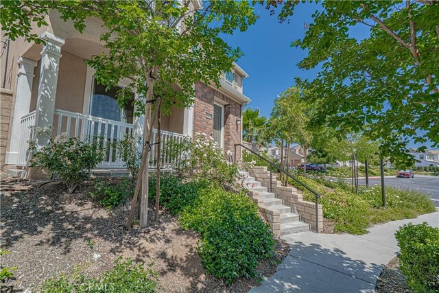 24270 Verdugo Cir, Valencia, CA 91354 - view of front facade with a porch, brick siding, stucco siding, and stairway