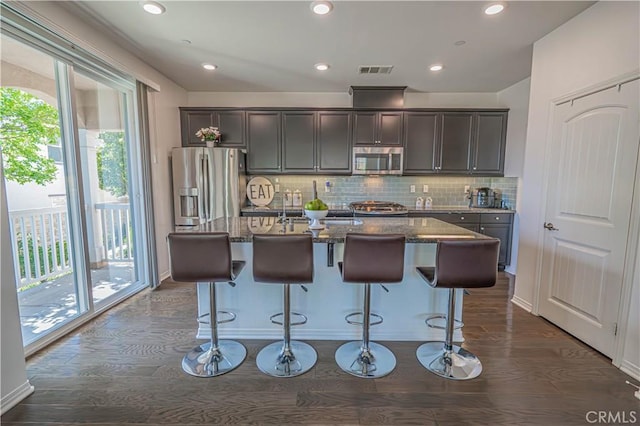 24270 Verdugo Cir, Valencia, CA 91354 - kitchen featuring stainless steel appliances, an island with sink, dark stone countertops, decorative backsplash, and recessed lighting