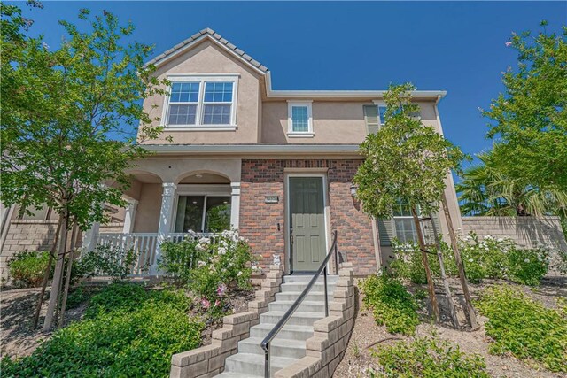 24270 Verdugo Cir, Valencia, CA 91354 - view of front facade featuring stucco siding, a porch, and brick siding