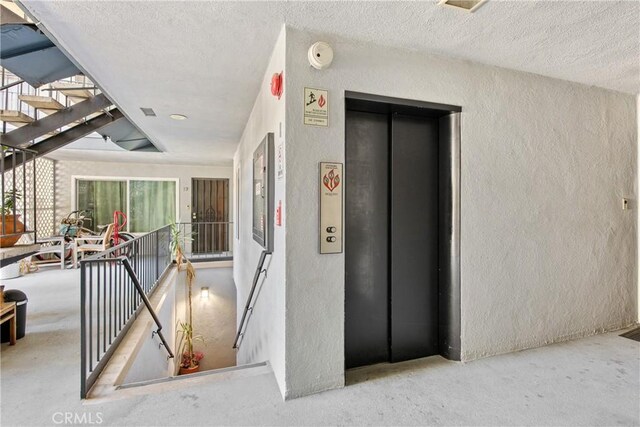 120 Alamitos Ave Unit 14, Long Beach, CA 90802 - corridor with a textured wall, elevator, and a textured ceiling