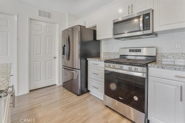 12956 9th Ave, Victorville, CA 92395 - kitchen featuring appliances with stainless steel finishes, white cabinets, light wood-style floors, and light stone countertops
