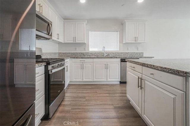 12956 9th Ave, Victorville, CA 92395 - kitchen with appliances with stainless steel finishes, light stone counters, white cabinetry, recessed lighting, and wood finished floors