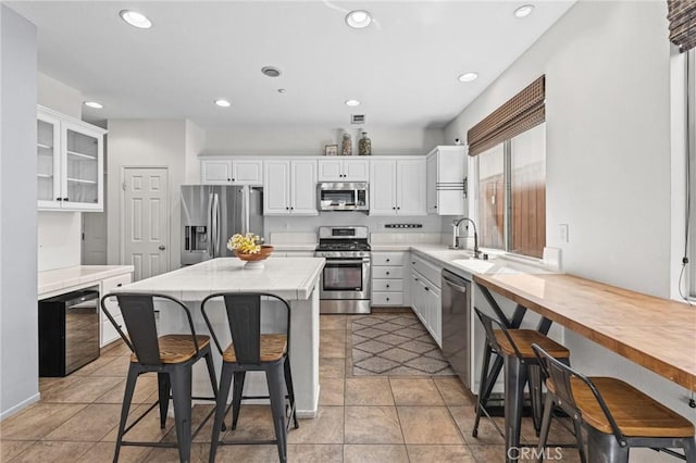 11317 Riverleaf Dr, Riverside, CA 92505 - kitchen featuring appliances with stainless steel finishes, a kitchen breakfast bar, white cabinetry, tile counters, and recessed lighting