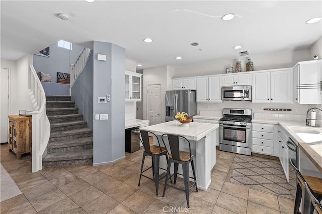 11317 Riverleaf Dr, Riverside, CA 92505 - kitchen with stainless steel appliances, white cabinetry, a breakfast bar area, a kitchen island, and recessed lighting