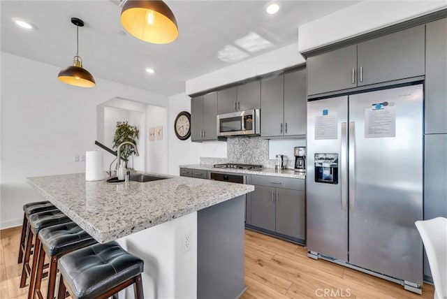2123 Crescent Moon, Upland, CA 91786 - kitchen featuring appliances with stainless steel finishes, light wood-style flooring, a breakfast bar, tasteful backsplash, and recessed lighting