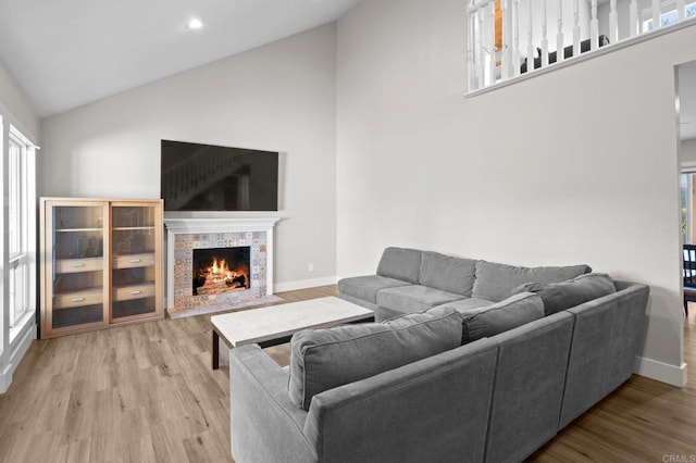 11052 Madrigal St, San Diego, CA 92129 - living room with high vaulted ceiling, light wood-style flooring, plenty of natural light, a warm lit fireplace, and recessed lighting