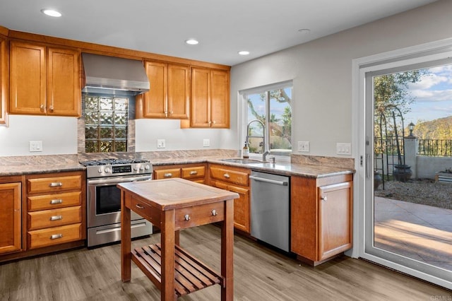 11052 Madrigal St, San Diego, CA 92129 - kitchen featuring stainless steel appliances, wall chimney exhaust hood, light wood-style flooring, brown cabinetry, and recessed lighting