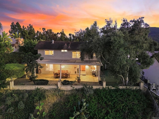 11052 Madrigal St, San Diego, CA 92129 - back of house at dusk featuring stucco siding, a metal roof, and a patio