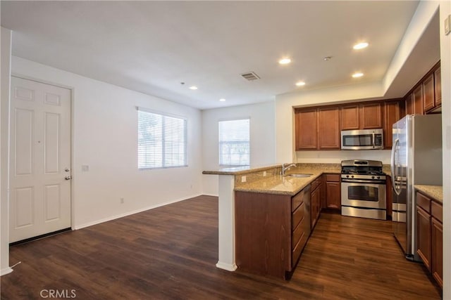 44939 Bellflower Ln Unit 118, Temecula, CA 92592 - kitchen with appliances with stainless steel finishes, a peninsula, dark wood-type flooring, light stone counters, and recessed lighting