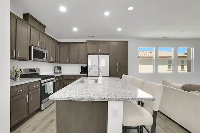 26149 Park Ave Unit 38, Loma Linda, CA 92354 - kitchen with appliances with stainless steel finishes, dark brown cabinets, a kitchen breakfast bar, light wood-type flooring, and open floor plan