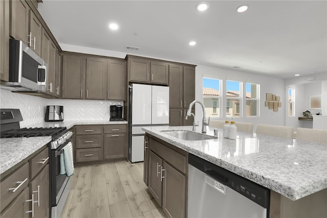 26149 Park Ave Unit 38, Loma Linda, CA 92354 - kitchen with appliances with stainless steel finishes, recessed lighting, dark brown cabinetry, a center island with sink, and light stone counters