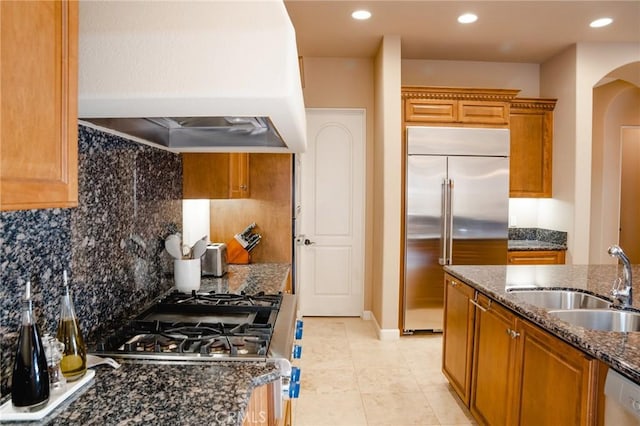 46614 Bradshaw Trl, La Quinta, CA 92253 - kitchen with custom exhaust hood, stainless steel built in fridge, dark stone counters, dishwasher, and arched walkways