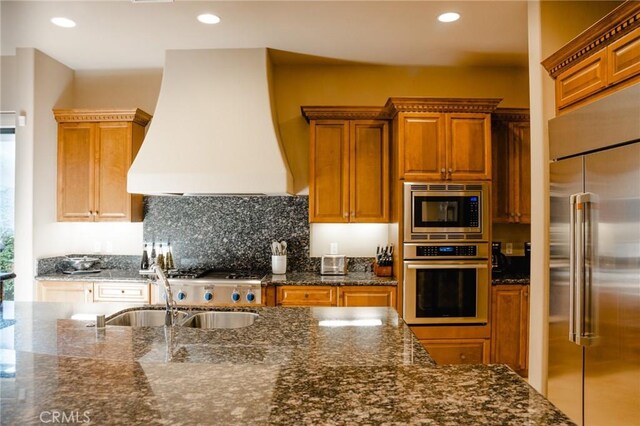 46614 Bradshaw Trl, La Quinta, CA 92253 - kitchen featuring built in appliances, custom range hood, brown cabinetry, dark stone countertops, and recessed lighting