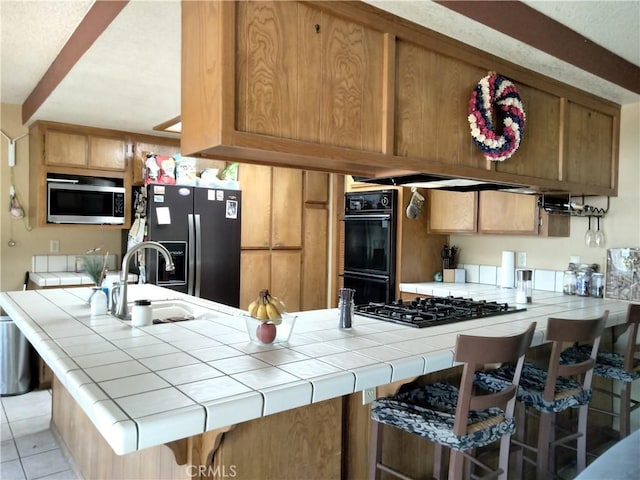 2390 Trinity Rd, Pinon Hills, CA 92372 - kitchen featuring black appliances, tile counters, a peninsula, and light tile patterned flooring