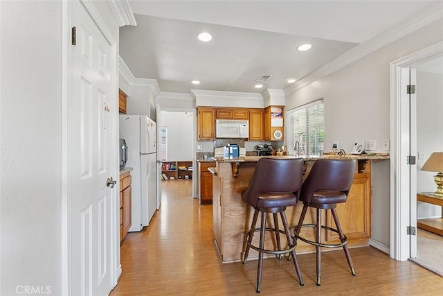 19080 Shakespeare Dr, Walnut, CA 91789 - kitchen featuring white appliances, brown cabinetry, light wood-type flooring, a breakfast bar area, and a peninsula